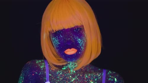 Studio Portrait of Young Asian Woman with UV Body Art and Make Up and Wearing Orange Wig Posing Over