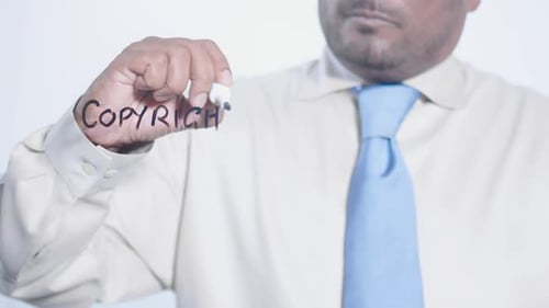 Man Writes Copyright on Clear Surface with Marker