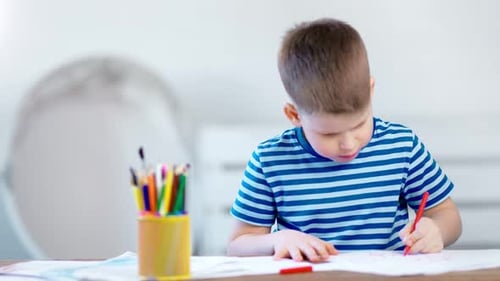 Cute Boy Drawing with Pencils at Table