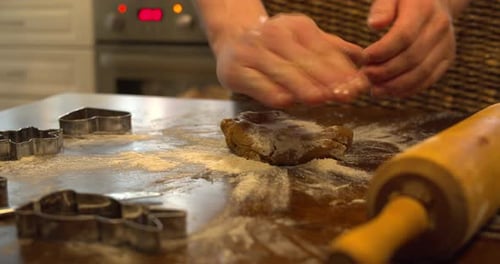 Flattening gingerbread dough with hands on a floured table. Close up