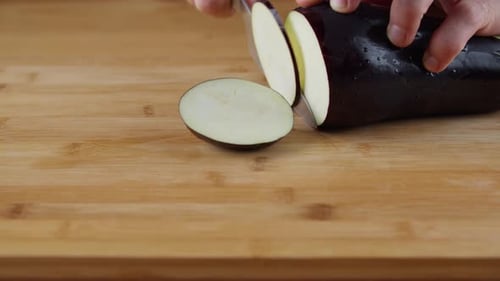 Slicing A Piece Of Seedless Eggplant With A Stainless Knife - close up