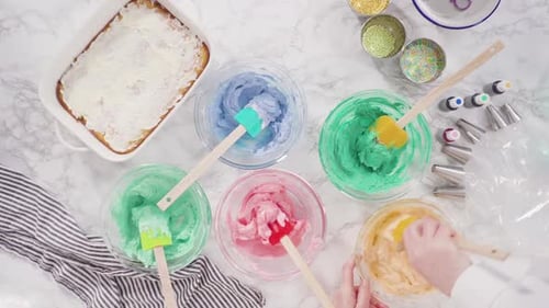 Flat lay. Mixing food coloring into Italian buttercream frosting.