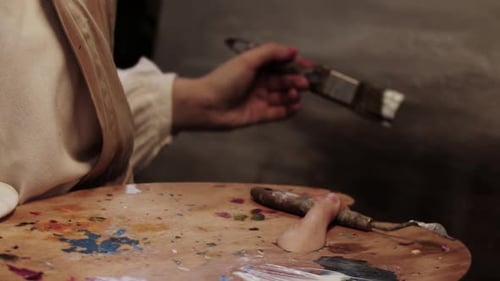 Young Woman Artist Putting on Finished Painting Protective Canvas of Paint