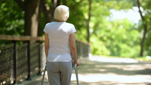 Elderly Woman Moving With Walking Frame at Rehabilitation Center Park