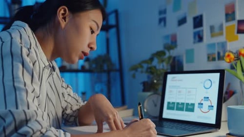 young asia lady freelance focus on laptop write worksheet finance graph account chart market plan.