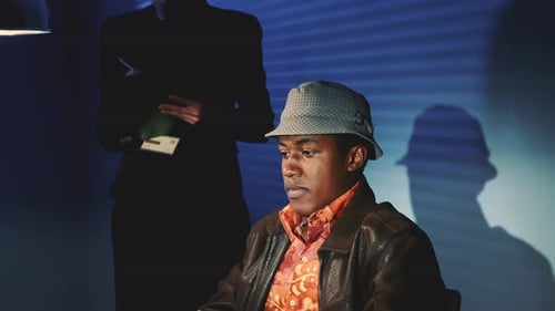 Close-up of Accused Black Man in Hat Covering His Face with His Hands During Interrogation