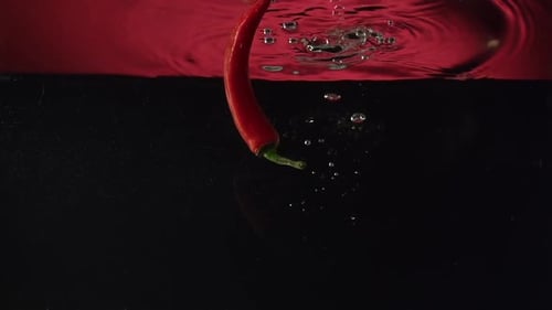 Chilli Peppers Splashing Into Water In Slow Motion
