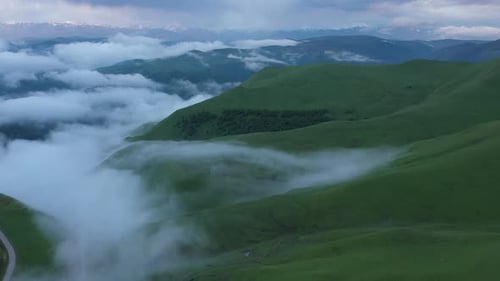Aerial view on the green fields at the mountains in the clouds and fog