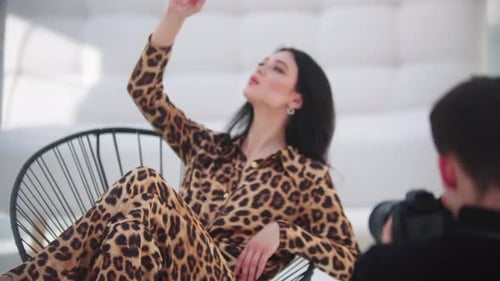 Young Attractive Model Woman in a Leopard Suit Having Photoshoot in White Studio