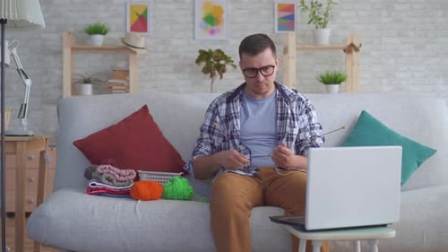 Man Knitting on Couch at Home