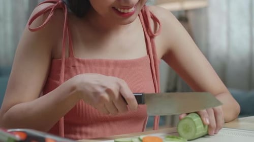 Close Up Of Smiling Asian Woman Enjoys Slicing The Cucumber At Home