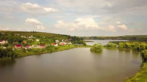 Aerial View of a Lake Surrounded with Yellow Agricultural Fields and Small Village Houses in Rural