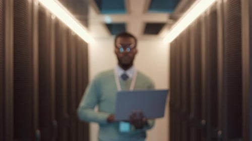 Professional IT Engineer Walking along Modern Server Room