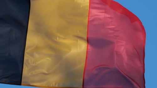 Belgian Flag Waving Proudly Against Blue Sky