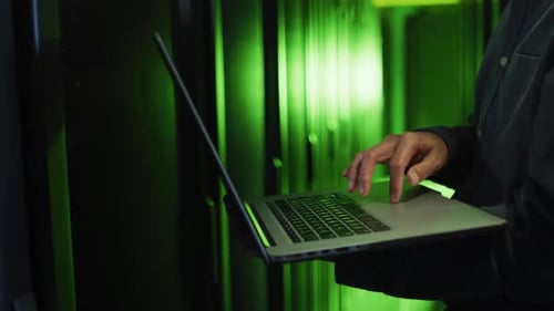 Mittelteil eines asiatischen männlichen IT-Technikers, der einen Laptop benutzt, um den Computerserver zu überprüfen