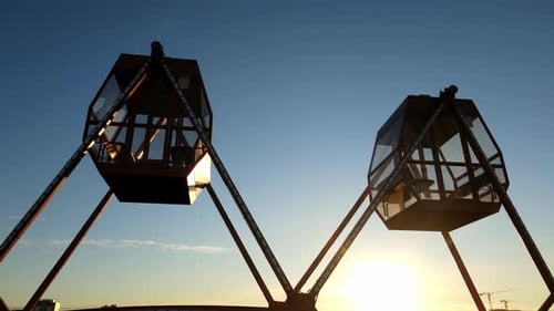 Cabins of a Carousel in the Backlight of the Rising Sun