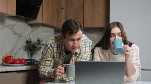 Young Couple Using Laptop in Modern Kitchen