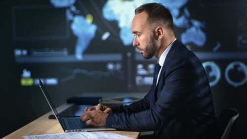 Konzentrierter Geschäftsmann, der am Laptop arbeitet und das Profit-Internet im Global Map Hi-Tech-Büro analysiert