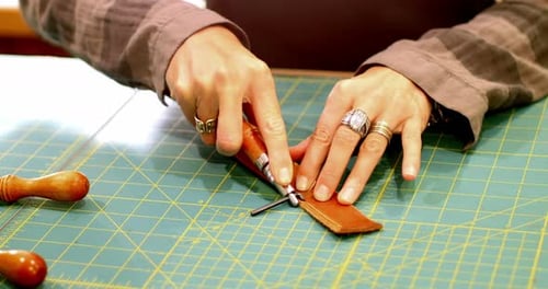 Hands Working on Leather With Tool