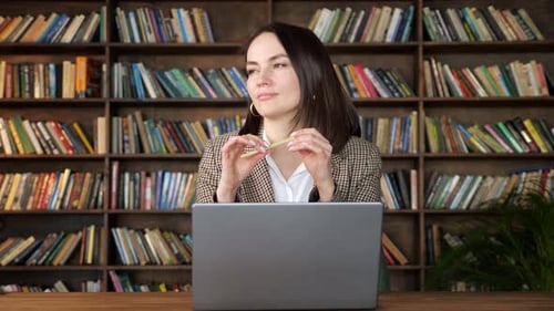 Thoughtful Woman with Laptop in Front of Bookshelves