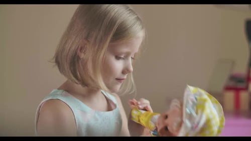 Porträt eines lächelnden kaukasischen Mädchens, das drinnen mit der Puppe spielt