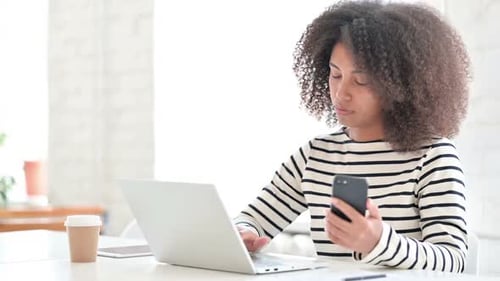 Young Adult Woman Working on Laptop and Using Phone