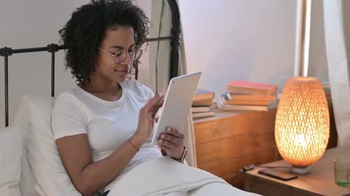 Woman Using Tablet in Bed at Home