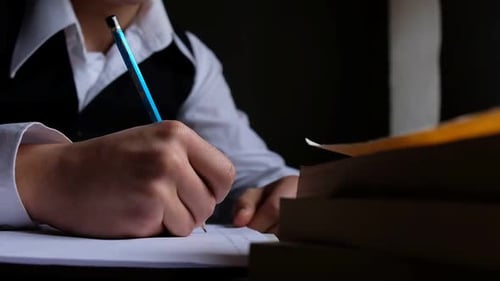 Student Writes on Paper With Pencil