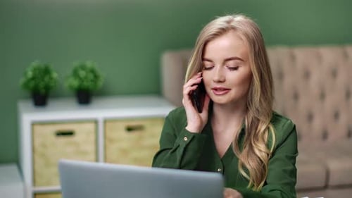 Woman Working on Laptop While Talking on Phone