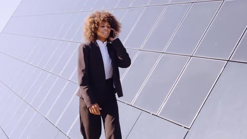 Businesswoman Walking, Talking on Phone Outside Office Building