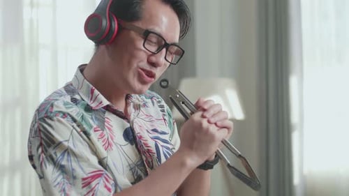 Man with Headphones Sings into Kitchen Tongs