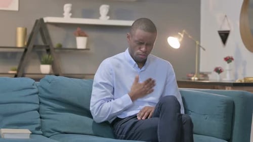 Young Adult Man Coughing While Sitting on Couch