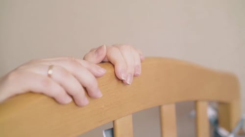 Young Adult Woman Looking at Baby in Crib