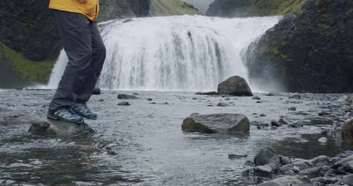 Man Legs Crop Crossing the River of Stjornarfoss Waterfall Near Kirkjubaejarklaustur at Iceland