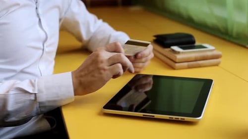 Adult Man Using Tablet and Credit Card at Table