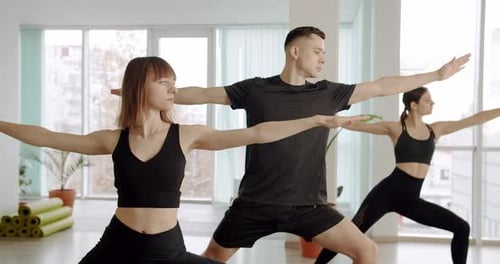 Young Adults Practice Yoga Indoors in Bright Studio