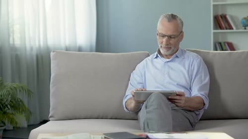Man Using Tablet Computer Relaxing on Couch