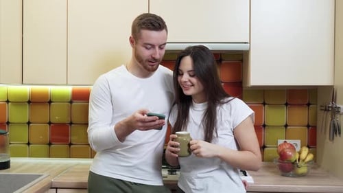 Couple Using Phone Together in Kitchen