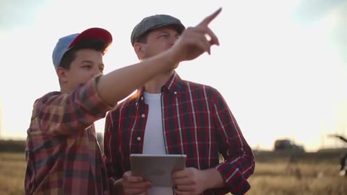 Farmer and Teen Using Tablet in Wheat Field