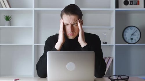 Man Massaging Temples at Office Desk