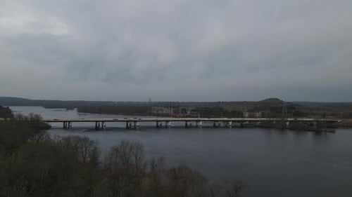 Herbstansicht der Brücke über den Fluss im Herbst. Versorgungstürme auf der anderen Seite des Wassers zu sehen.