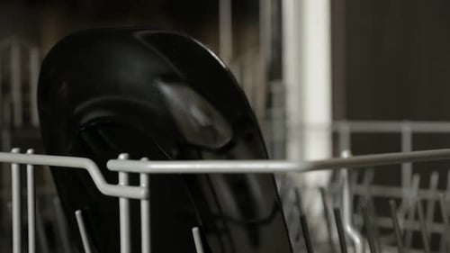Person Loading Black Plates Into Dishwasher