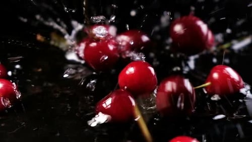 Red Cherries Falling and Splashing onto Black Surface