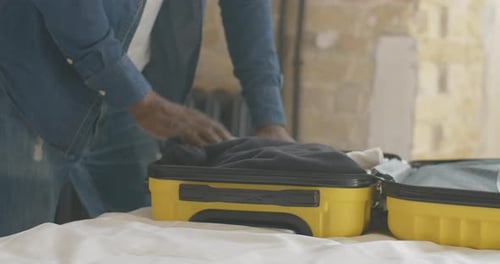 Adult Packs a Yellow Suitcase for Travel
