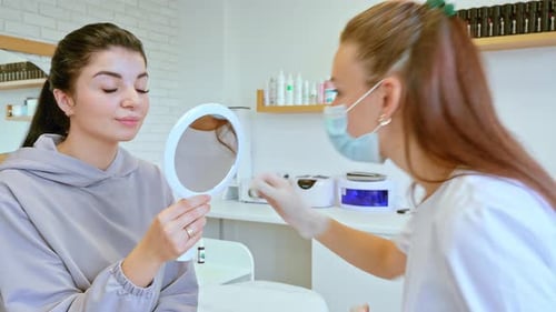 Woman Inspects Lips after Cosmetic Treatment in Beauty Salon