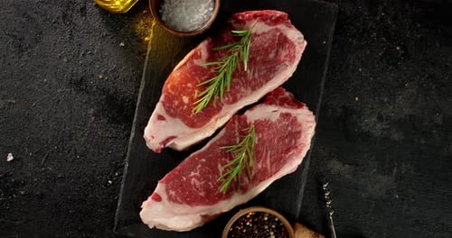 Two Raw Steaks Garnished with Rosemary