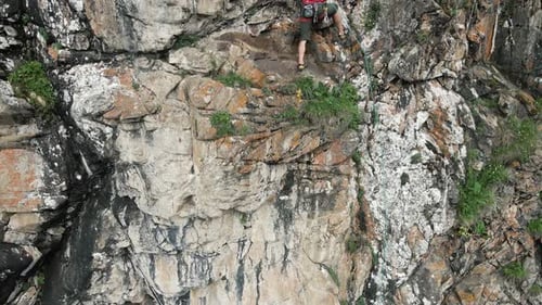 Man Athlette-Klettern auf dem hohen Felsen in den Bergen