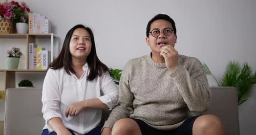 Cheerful couple cheering football game on TV