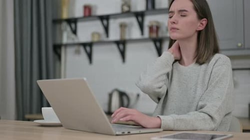 Woman Massaging Neck While Working on Laptop