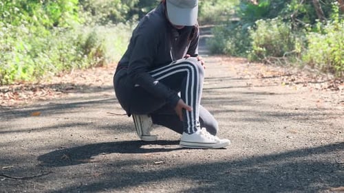 Woman Holds Ankle in Pain on Walking Path